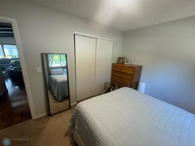 bedroom with a textured ceiling, carpet, and a closet