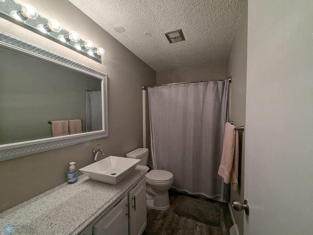 bathroom with vanity, curtained shower, a textured ceiling, hardwood / wood-style flooring, and toilet