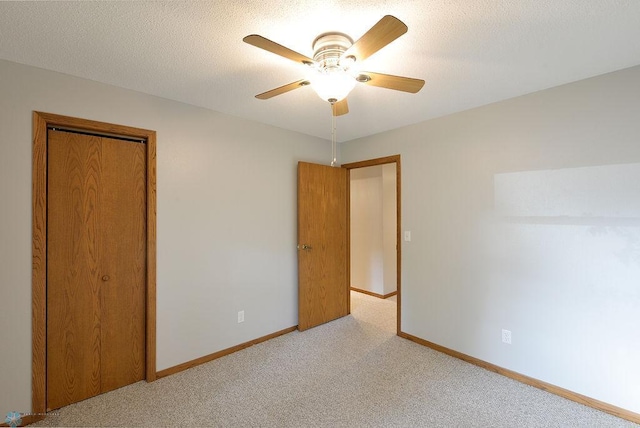 unfurnished bedroom featuring a textured ceiling, ceiling fan, light colored carpet, and a closet