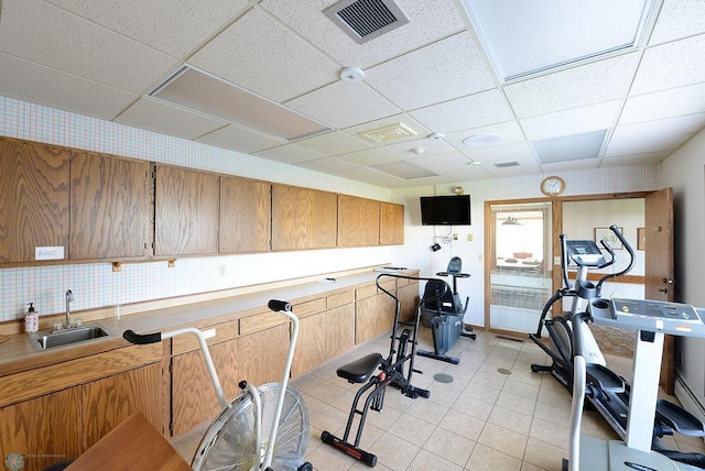 workout area with light tile patterned floors, a drop ceiling, and sink