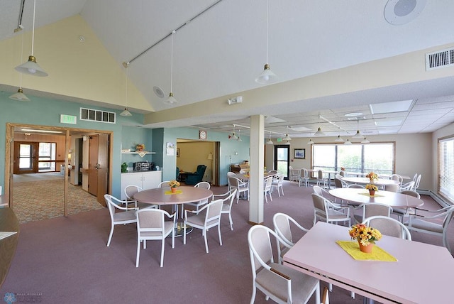 carpeted dining area featuring high vaulted ceiling and rail lighting