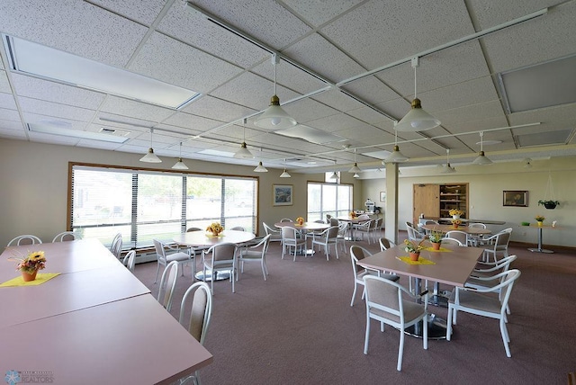 carpeted dining area with a paneled ceiling