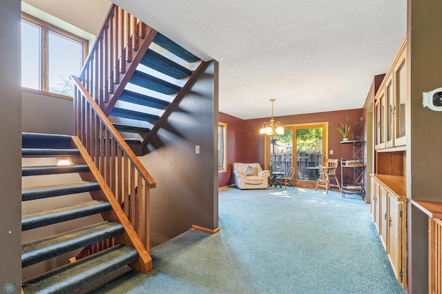 staircase with a textured ceiling, a chandelier, and a wealth of natural light