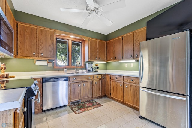 kitchen featuring light tile patterned floors, sink, ceiling fan, and stainless steel appliances