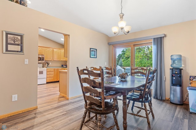 dining room featuring a notable chandelier, light wood-type flooring, and lofted ceiling