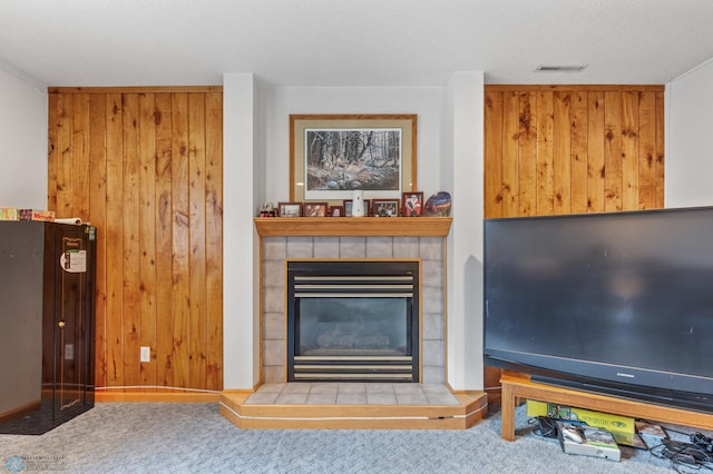 carpeted living room with a tile fireplace and wood walls