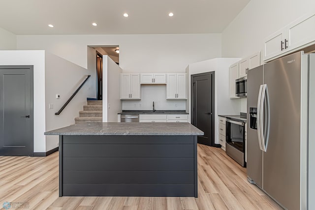 kitchen with white cabinets, sink, stainless steel appliances, and light hardwood / wood-style floors