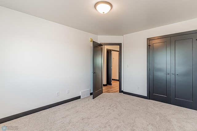 unfurnished bedroom with light carpet and a closet