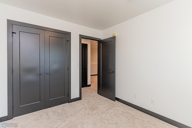 unfurnished bedroom featuring a closet and light colored carpet