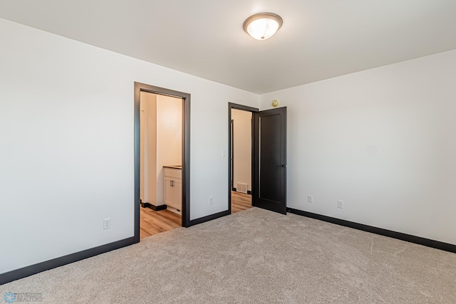 unfurnished bedroom featuring light carpet and connected bathroom