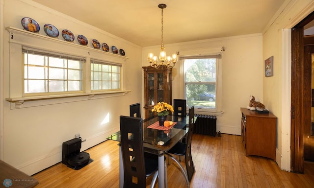 dining room with radiator, hardwood / wood-style flooring, crown molding, and a notable chandelier