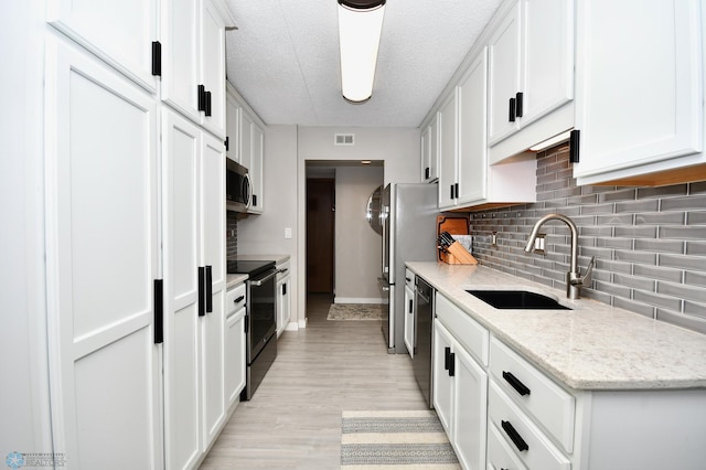 kitchen featuring appliances with stainless steel finishes, sink, light hardwood / wood-style flooring, and white cabinets