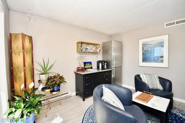 sitting room with light hardwood / wood-style flooring, a textured ceiling, and baseboard heating