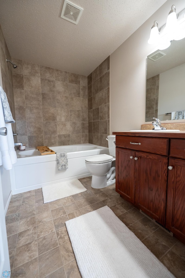 full bathroom featuring tiled shower / bath, vanity, a textured ceiling, tile walls, and toilet