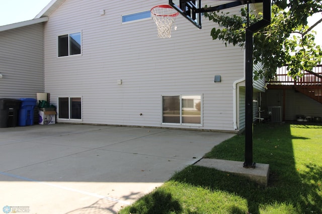 rear view of property with central AC unit, a lawn, and a patio area