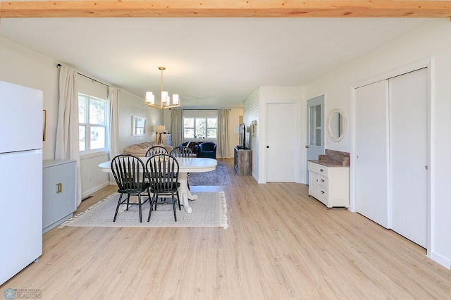 dining area featuring an inviting chandelier, light wood-type flooring, and beamed ceiling