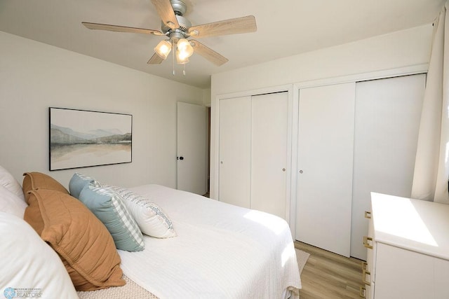 bedroom with two closets, light hardwood / wood-style floors, and ceiling fan