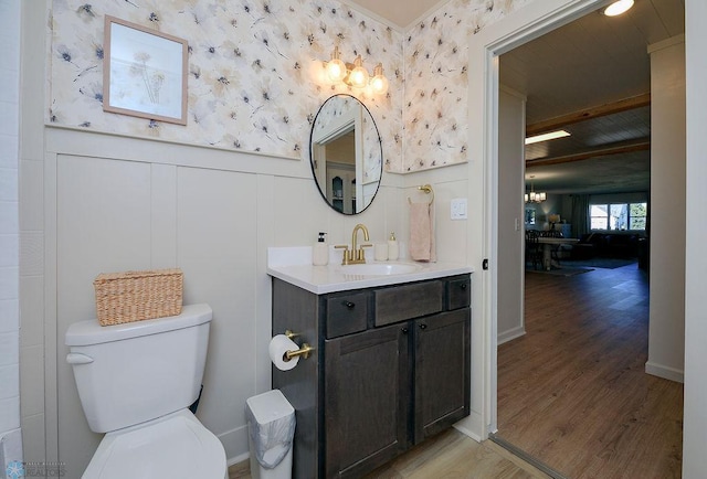 bathroom with vanity, beam ceiling, hardwood / wood-style flooring, toilet, and a notable chandelier