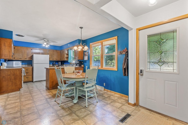 dining area featuring ceiling fan with notable chandelier