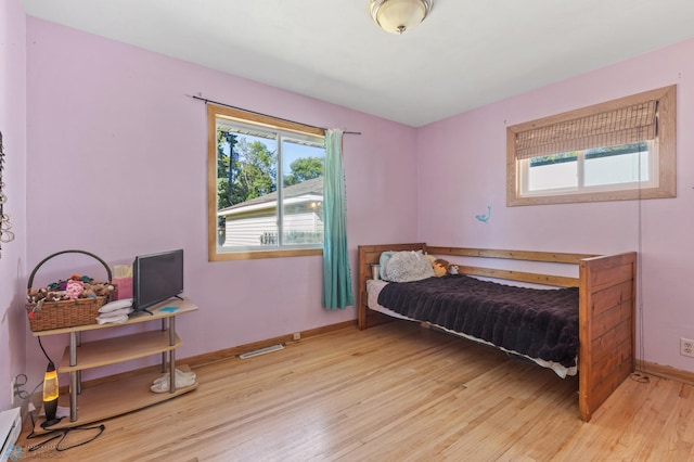 bedroom with baseboard heating and light hardwood / wood-style flooring