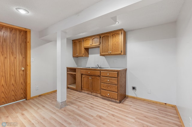 kitchen featuring light wood-type flooring, sink, and a textured ceiling