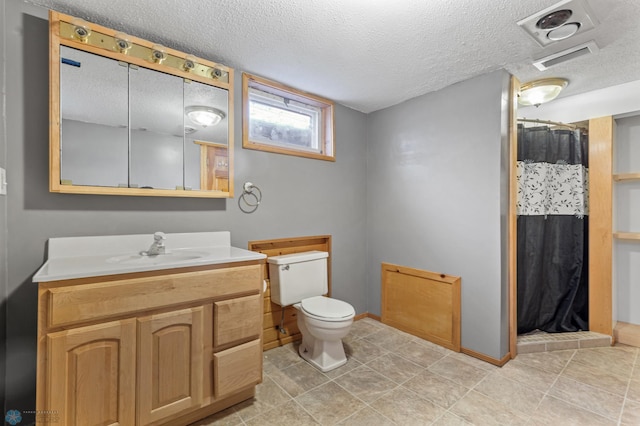 bathroom featuring toilet, vanity, and a textured ceiling