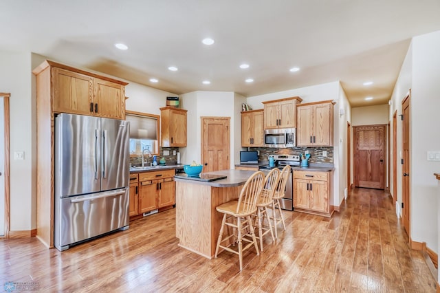 kitchen featuring sink, light hardwood / wood-style flooring, stainless steel appliances, a center island, and a breakfast bar area