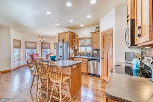 kitchen featuring hanging light fixtures, light hardwood / wood-style floors, backsplash, stainless steel appliances, and a notable chandelier