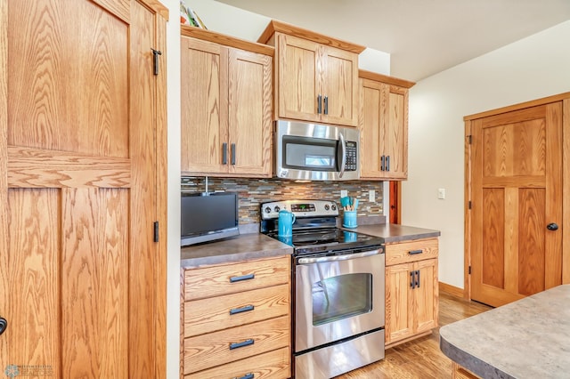 kitchen with light brown cabinets, stainless steel appliances, tasteful backsplash, and light hardwood / wood-style flooring