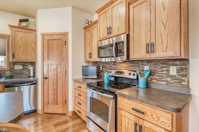 kitchen featuring light brown cabinetry, appliances with stainless steel finishes, light hardwood / wood-style floors, and tasteful backsplash