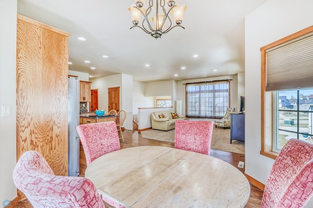 dining space featuring an inviting chandelier, light wood-type flooring, and plenty of natural light