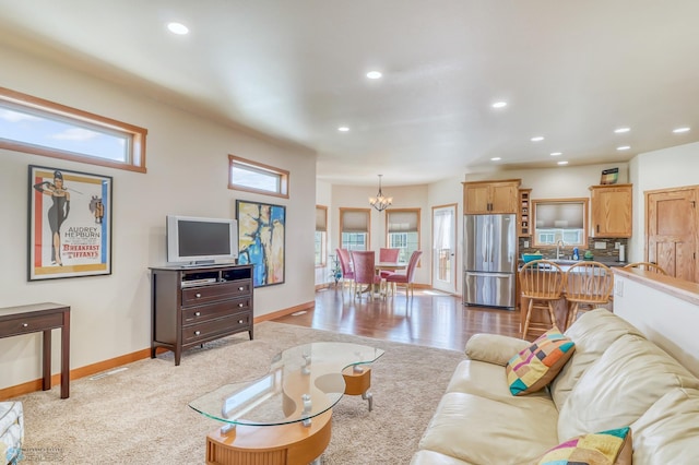 living room with an inviting chandelier, light hardwood / wood-style flooring, and sink