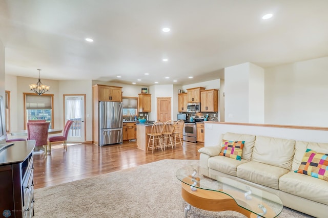 living room with a notable chandelier, light hardwood / wood-style flooring, and sink