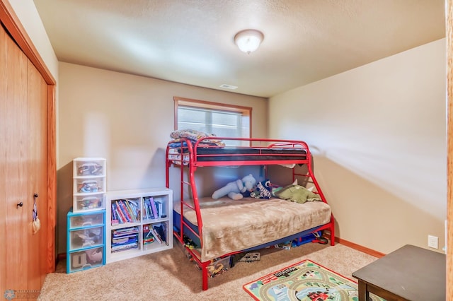 carpeted bedroom with a textured ceiling and a closet