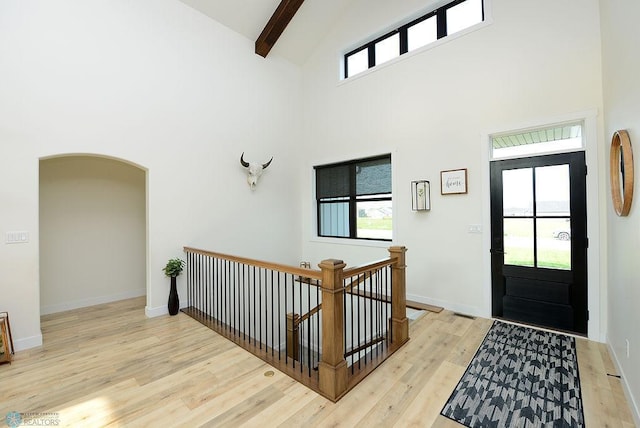 foyer with beamed ceiling, plenty of natural light, light hardwood / wood-style floors, and high vaulted ceiling