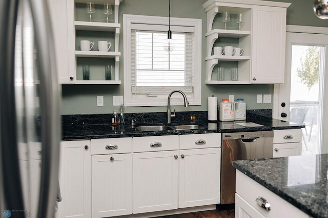 kitchen with stainless steel dishwasher, white cabinetry, dark stone counters, and a wealth of natural light