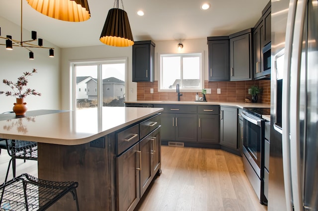 kitchen featuring a breakfast bar area, a center island, stainless steel appliances, and plenty of natural light