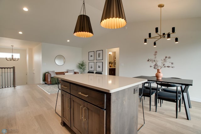 kitchen with pendant lighting, light wood-type flooring, a center island, an inviting chandelier, and dark brown cabinetry