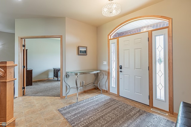 entryway featuring light carpet and a chandelier