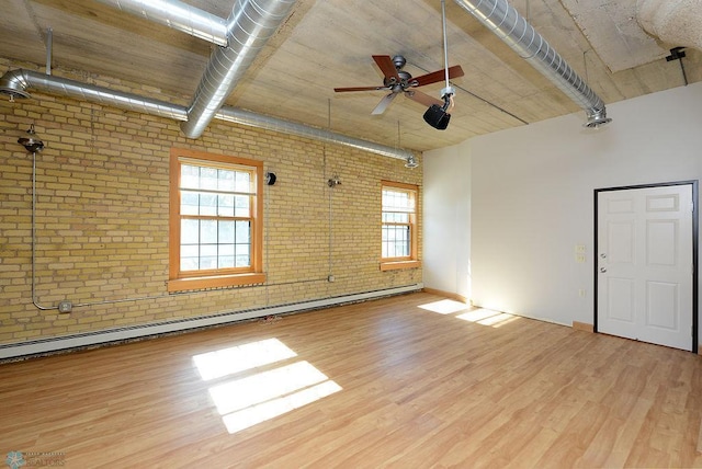 spare room featuring light hardwood / wood-style floors, ceiling fan, a baseboard radiator, and brick wall