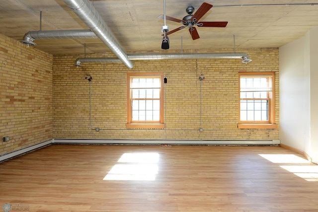 unfurnished room with light wood-type flooring, ceiling fan, and brick wall