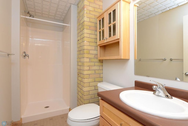 bathroom featuring vanity, toilet, brick wall, walk in shower, and tile patterned flooring