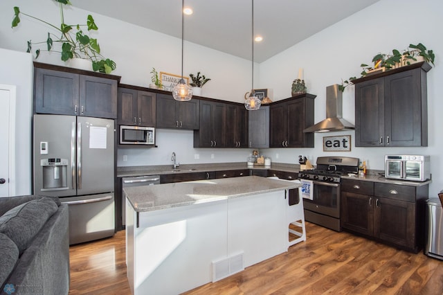 kitchen featuring pendant lighting, a center island, dark wood-type flooring, wall chimney exhaust hood, and appliances with stainless steel finishes