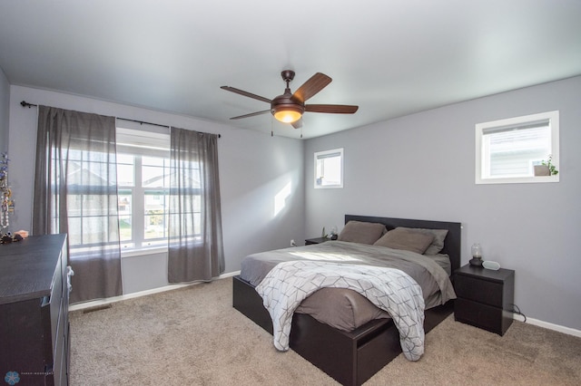 carpeted bedroom with multiple windows and ceiling fan