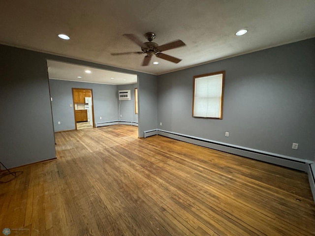 spare room featuring light hardwood / wood-style floors, baseboard heating, ceiling fan, and a wall unit AC