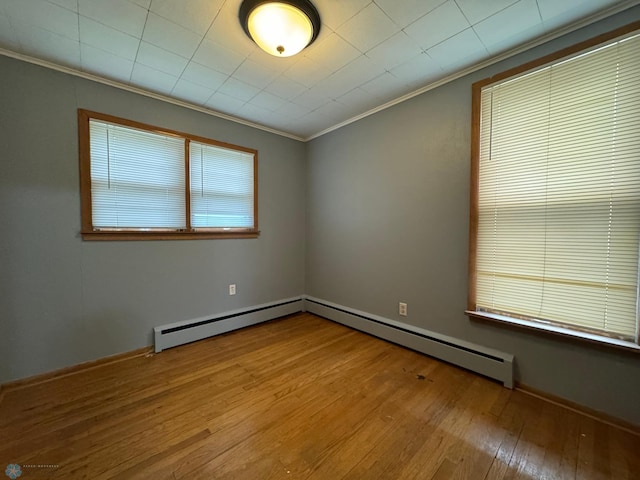 unfurnished room with light wood-type flooring, crown molding, and a baseboard heating unit