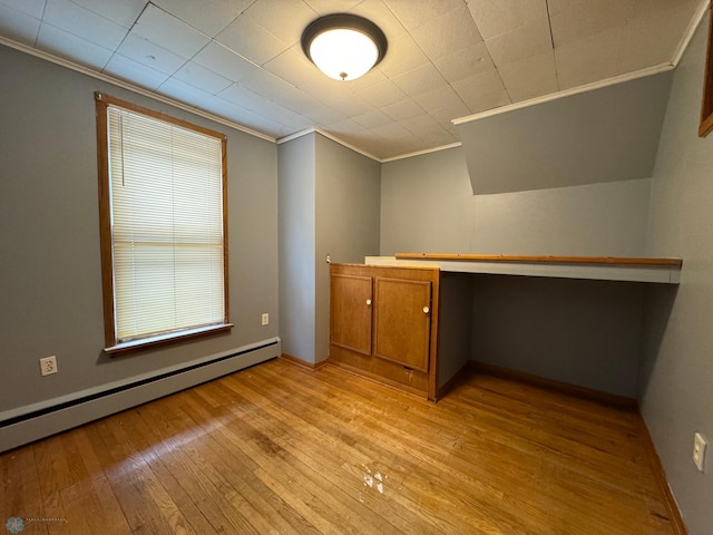 interior space featuring light hardwood / wood-style flooring, a baseboard heating unit, built in desk, and ornamental molding