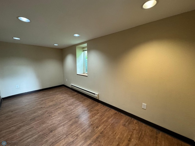 unfurnished room with dark hardwood / wood-style flooring and a baseboard heating unit