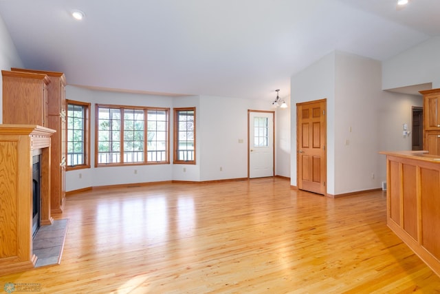 unfurnished living room featuring vaulted ceiling, light hardwood / wood-style flooring, and a chandelier