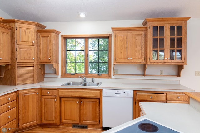 kitchen featuring white dishwasher, light wood-type flooring, sink, and a textured ceiling